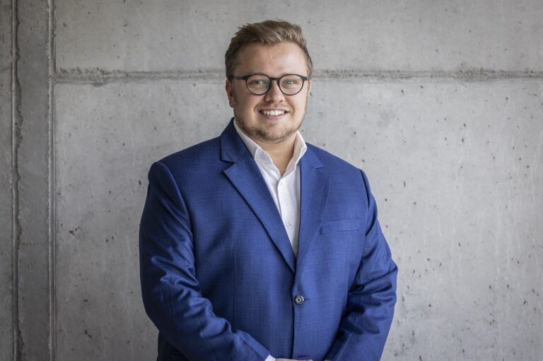 Ein Foto von dem Mann Niklas Rückwald, Start-up-Berater und Connector HSG, vor einer grauen Wand.