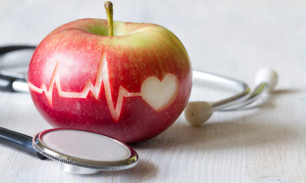 Heartbeat line on red apple and stethoscope, healthy heart diet concept background